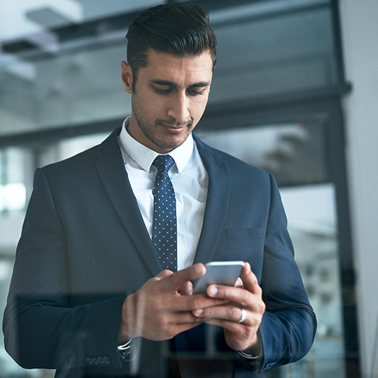 podnikatel kontroluje svůj mobilní telefon